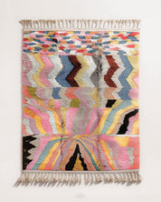 Multicolored abstract pink moroccan rug with fringe on a white background