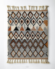 Handmade Moroccan rug with grey geometric pattern in vintage style and tassels on a white background