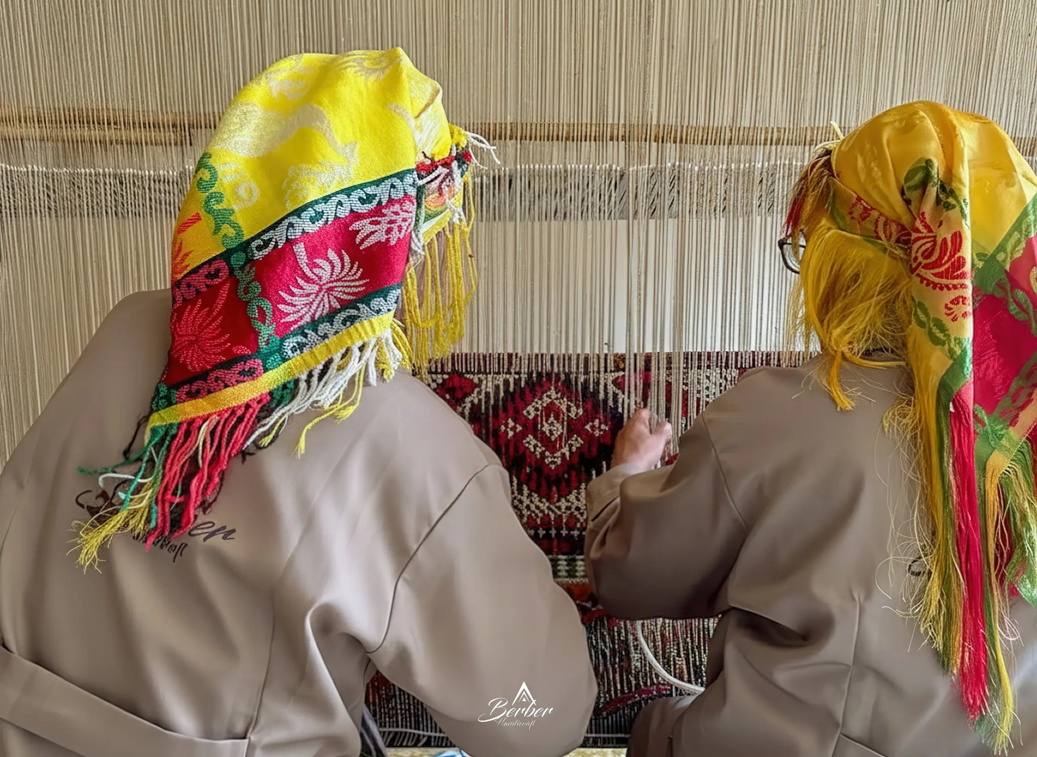 Two weavers working on a traditional loom, to make a Moroccan berber rug.
