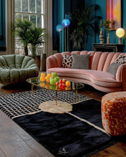 Black moroccan rug on a Modern living room with a pink sofa, green armchair, and colorful decor.