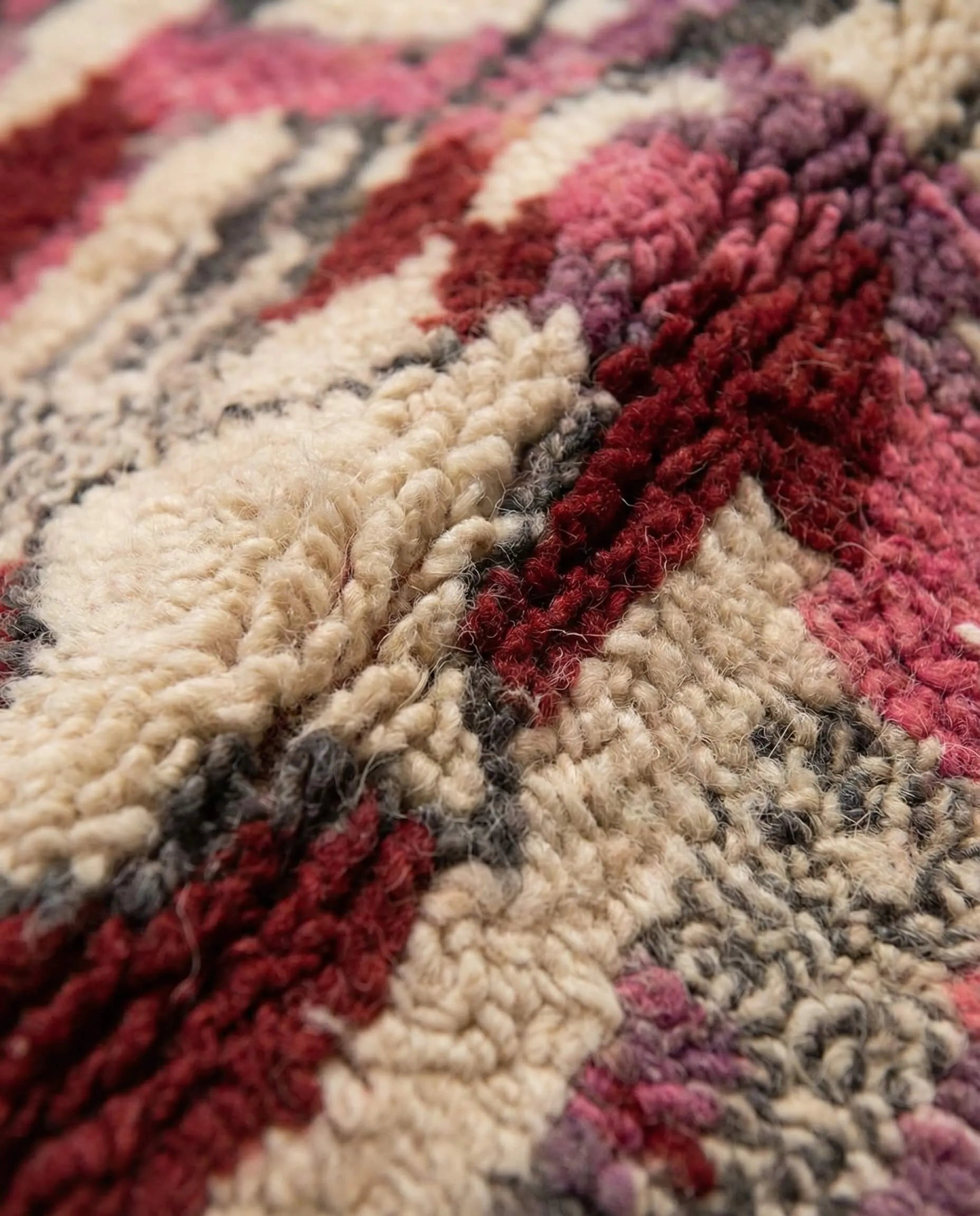Close-up of a textured rug with red, beige, and purple patterns