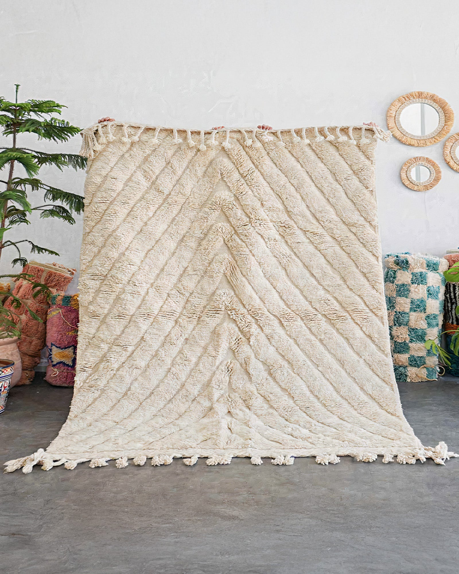 Textured wall hanging with tassels in a room setting with decor elements.