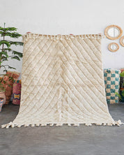 Textured wall hanging with tassels in a room setting with decor elements.