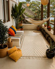 Cozy indoor setting with a rug, pillows, and plants on a balcony.