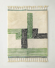 Woven Moroccan rug with striped green and black lines on a plain background