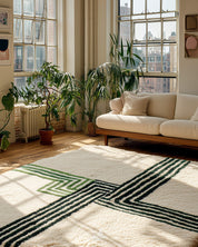 Living room with a striped green and ivory wool rug, white sofa, and large windows.