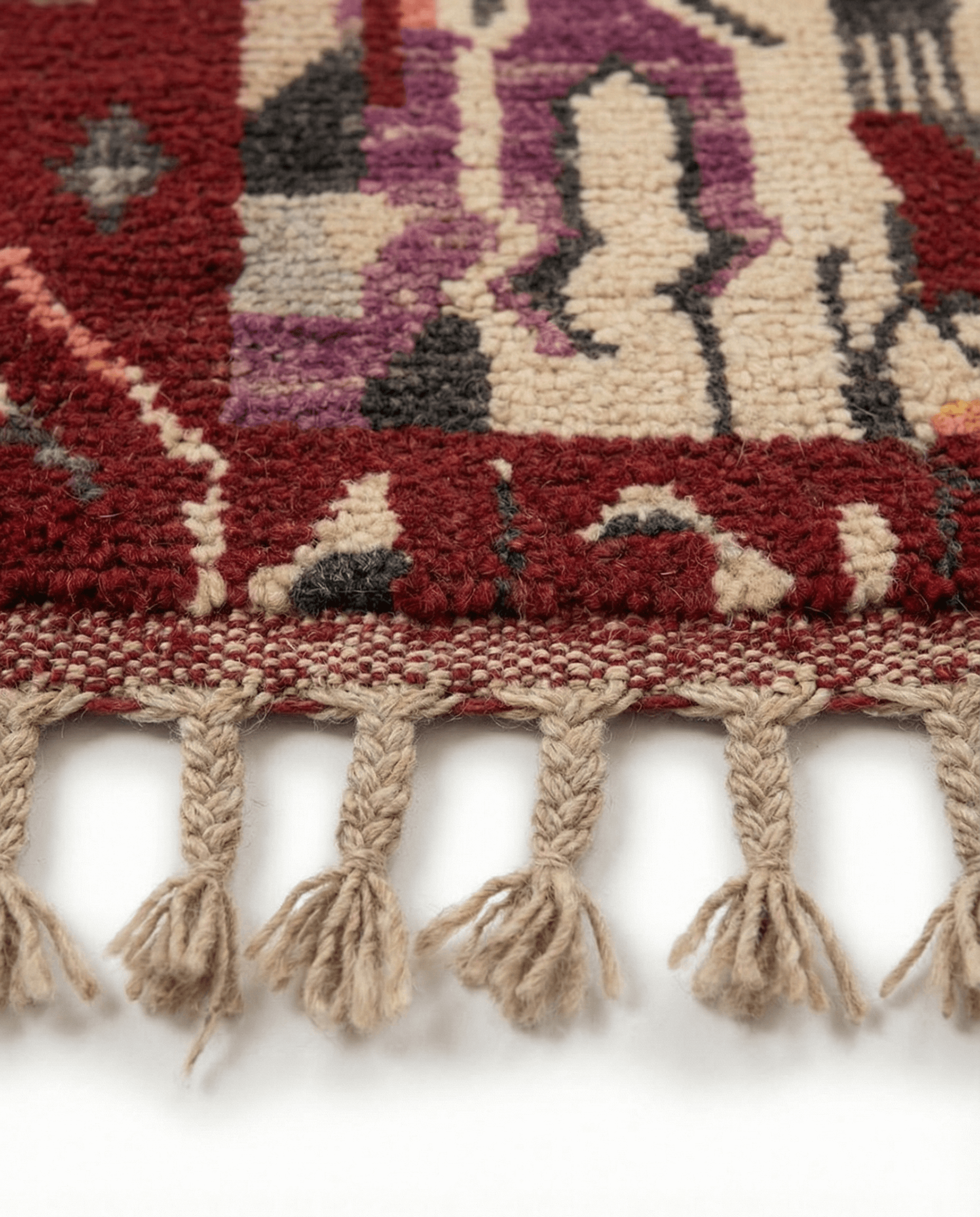 Close-up of a patterned rug with tassels on a white background