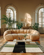 Modern living room with a white and green geometric Berber rug, beige sectional sofa, coffee table, and decorative plants.